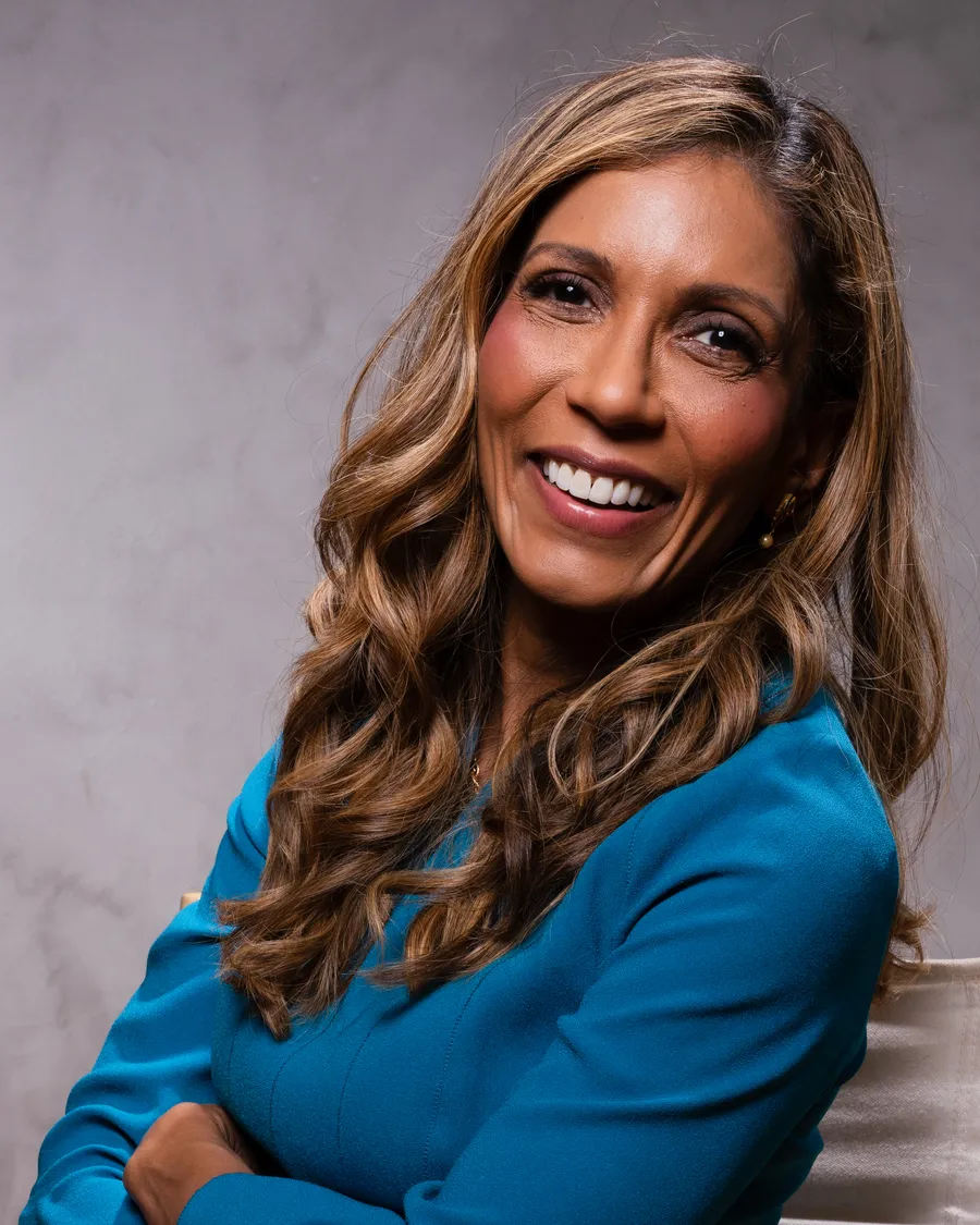 Dr. Noorhasan in a teal dress, seated on a director’s chair
